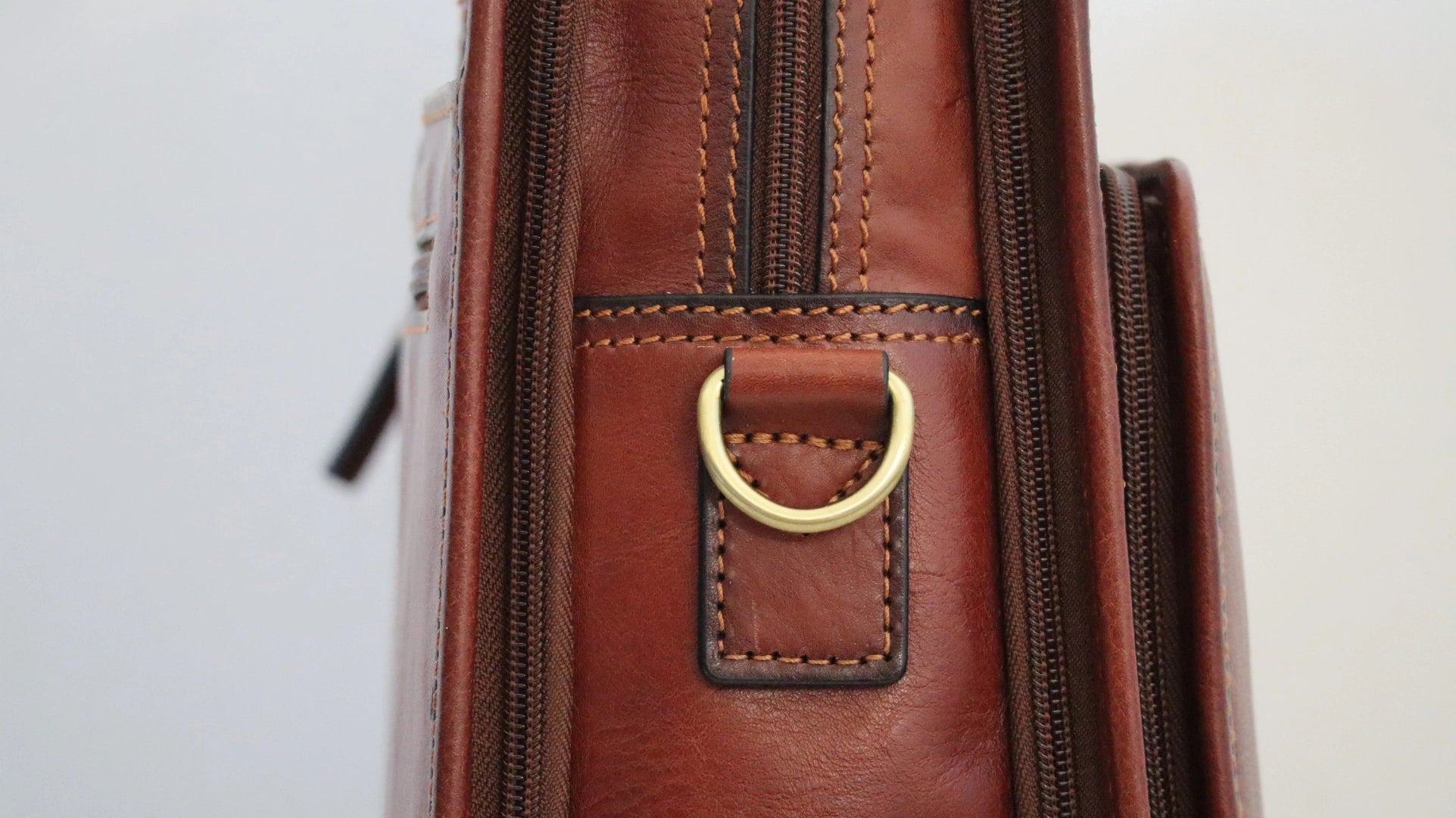 porte ordinateur en cuir marron, finition dorée - vue de détail accroche bandoulière en laiton 